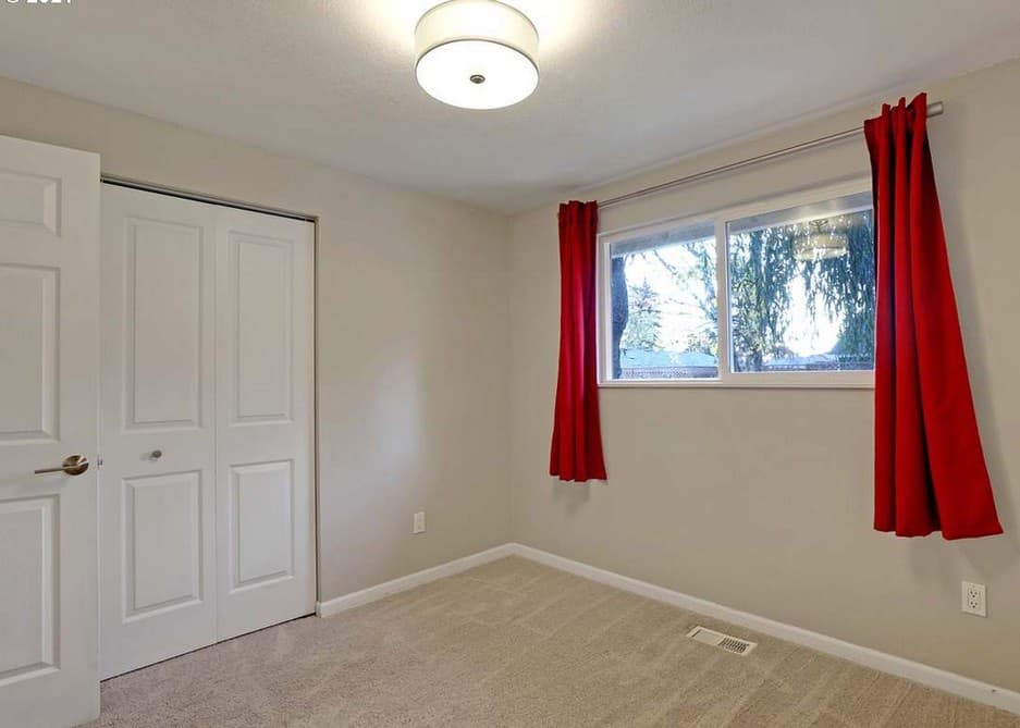A carpeted bedroom with a window and closet