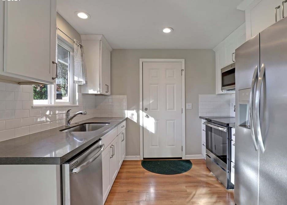 Kitchen with white cabinets, subway tile, and stainless appliances