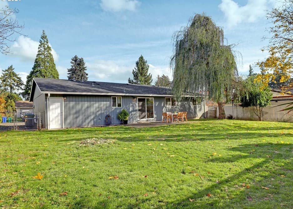 Large fenced backyard with a lawn and mature trees